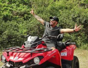 Um homem está feliz em um quadriciclo vermelho alugado em Arraial Feiras em Arraial do cabo